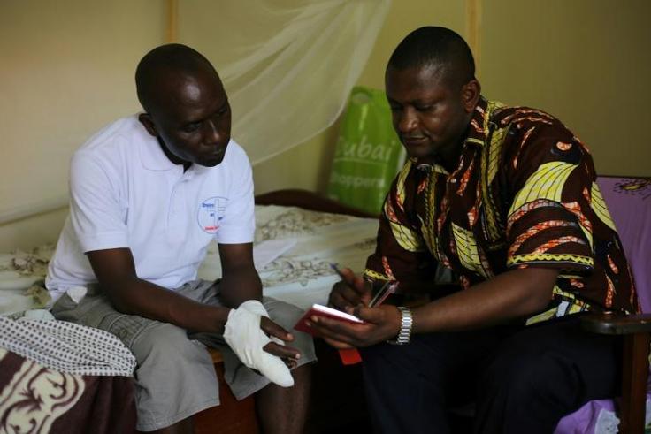 Father Guy-Robert Mandro, shown with a visitor to his home as he recovers from his maiming