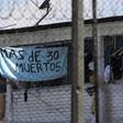 Inmates at Bogota's La Modelo prison hold up a sign saying, "More than 30 Dead" after a night of rioting in one of Colombia's biggest prisons, on March 22, 2020