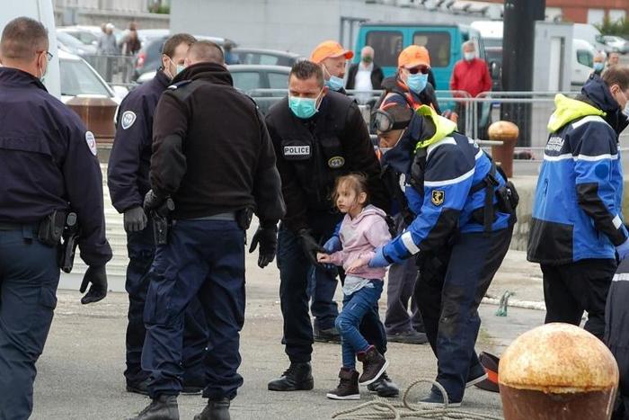 French police, wearing protective masks against the coronavirus, with young migrants picked up off Calais as they tried to get to Britain by boat