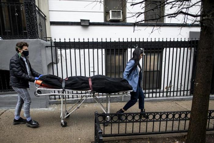 Alisha Narvaez (R) and Lily Sage Weinrieb of International Funeral & Cremation Services transport a body on April 24 in the Harlem neighborhood of New York