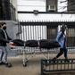 Alisha Narvaez (R) and Lily Sage Weinrieb of International Funeral & Cremation Services transport a body on April 24 in the Harlem neighborhood of New York
