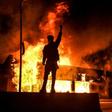 Un manifestant devant un bâtiment incendie dans la ville américaine de Minneapolis dans la nuit du 29 au 30 mai 2020