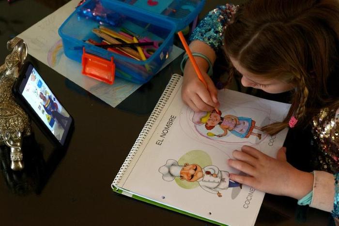 A six-year-old Spanish girl studies while watching a video of her teacher in Sevilla on April 14, 2020 amid a national lockdown to stop the spread of the COVID-19 coronavirus