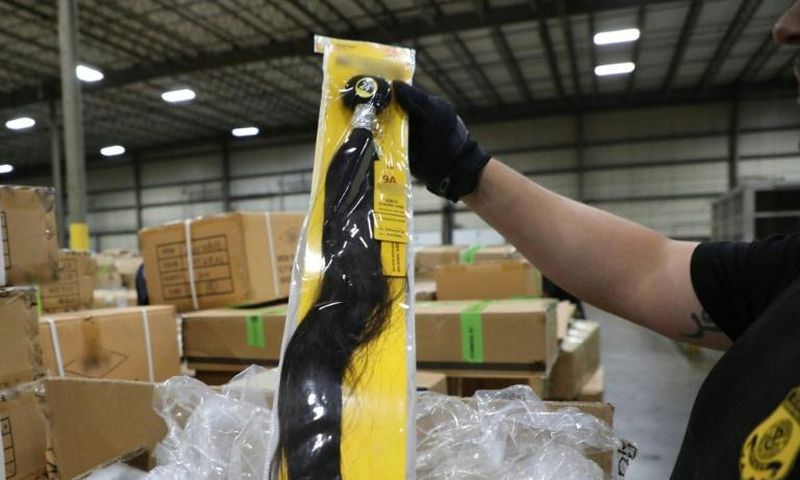 A US Customs and Border Protection officer at the Port of New York/Newark inspects a shipment of hair pieces and accessories from China suspected to have been made with forced or prison labor