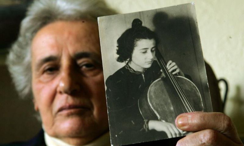 Holocaust survivor Anita Lasker-Wallfisch, pictured here in 2005, holds up a portrait of herself playing the cello in Berlin before World War II