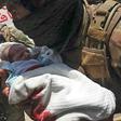 An Afghan security officer carries a newborn baby from a hospital after it is attacked in Kabul