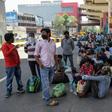 Migrant workers and their families wait for transport back to their home towns