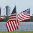 A SpaceX Falcon 9 rocket with the Crew Dragon spacecraft looms in the distance at launch complex 39A as American flags flutter in the wind, at the Kennedy Space Center in Florida on May 29