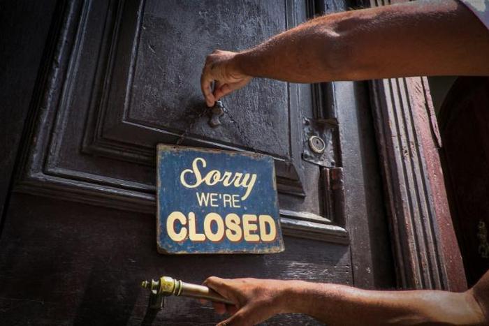 An employee of Havana's El Cafe coffee shop puts up a sign that has become a familiar sight during the coronavirus pandemic