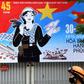 A woman walks next to a hoarding marking the 45th anniversary of the fall of Saigon, in Hanoi