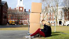A Harvard student sits with her belongings before returning home on March 12, 2020, as students left campus due to the coronavirus pandemic