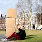 A Harvard student sits with her belongings before returning home on March 12, 2020, as students left campus due to the coronavirus pandemic