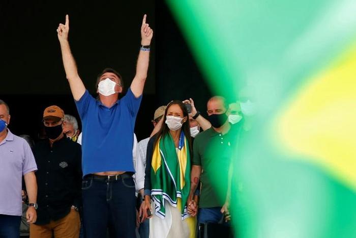 Brazilian President Jair Bolsonaro (C) compares the coronavirus to a "little flu," condemns the "hysteria" surrounding it and is urging the country to get back to work to stop an economic crash