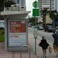 People walk past a billboard in Miami Beach discussing sea level rise: dozens of trucks have started dumping hundreds of thousands of tons of sand on Miami Beach as part of US government measures to protect Florida's tourist destinations against the ef...