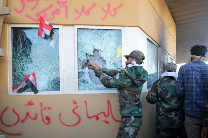 Members of Iraq's Hashed al-Shaabi, a mostly Shiite network of armed groups trained and armed by powerful neighbour Iran, smash a window at the US embassy in Baghdad in December 2019
