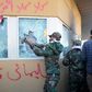 Members of Iraq's Hashed al-Shaabi, a mostly Shiite network of armed groups trained and armed by powerful neighbour Iran, smash a window at the US embassy in Baghdad in December 2019