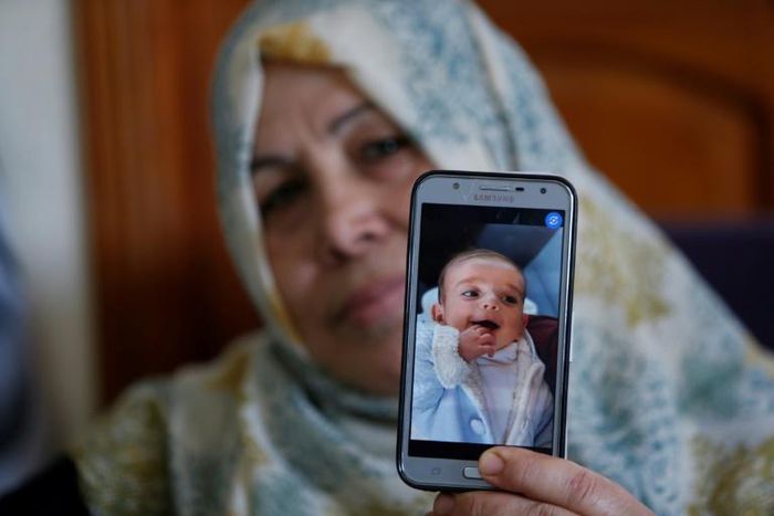The grandmother of Palestinian baby Omar Yagi displays a picture of him taken before his death in Gaza last week from a serious heart condition he had been due to receive life-saving surgery in Israel for