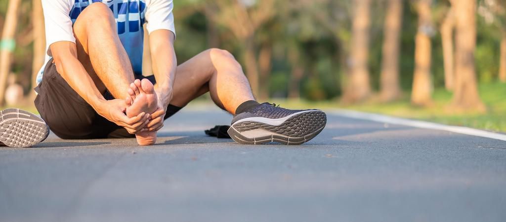 Low Section Of Man Touching Leg In Pain On Road