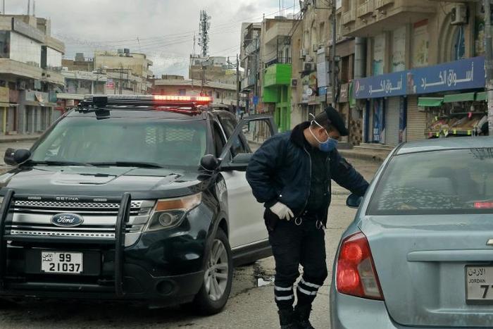 A policeman speaks to a driver at a checkpoint in the Jordanian capital Amman during a nationwide curfew imposed to control the spread of the novel coronavirus
