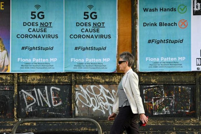 A pedestrian walks past public service announcement posters, negating a conspiracy that 5G telecommunications technology causes the coronavirus, in Melbourne, Australia