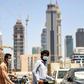 Foreign workers clad in masks to protect against coronavirus push bicycles along a street in the Satwa district of Dubai