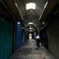 A woman walks past closed shops along a deserted alley in the Old City of Jerusalem