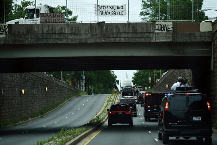 Protesters display signs over President Donald Trump's motorcade in Washington, DC