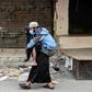 A woman carries a disabled man wearing a protective face mask in the Sabra refugee camp in Lebanon where vulnerable Syrian and Palestinian refugees are bracing for the coronavirus