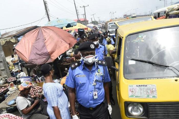 Lagos Police Commissioner Hakeem Odumosu squeezes his way through a market to monitor compliance with  measures to curb the spread of coronavirus