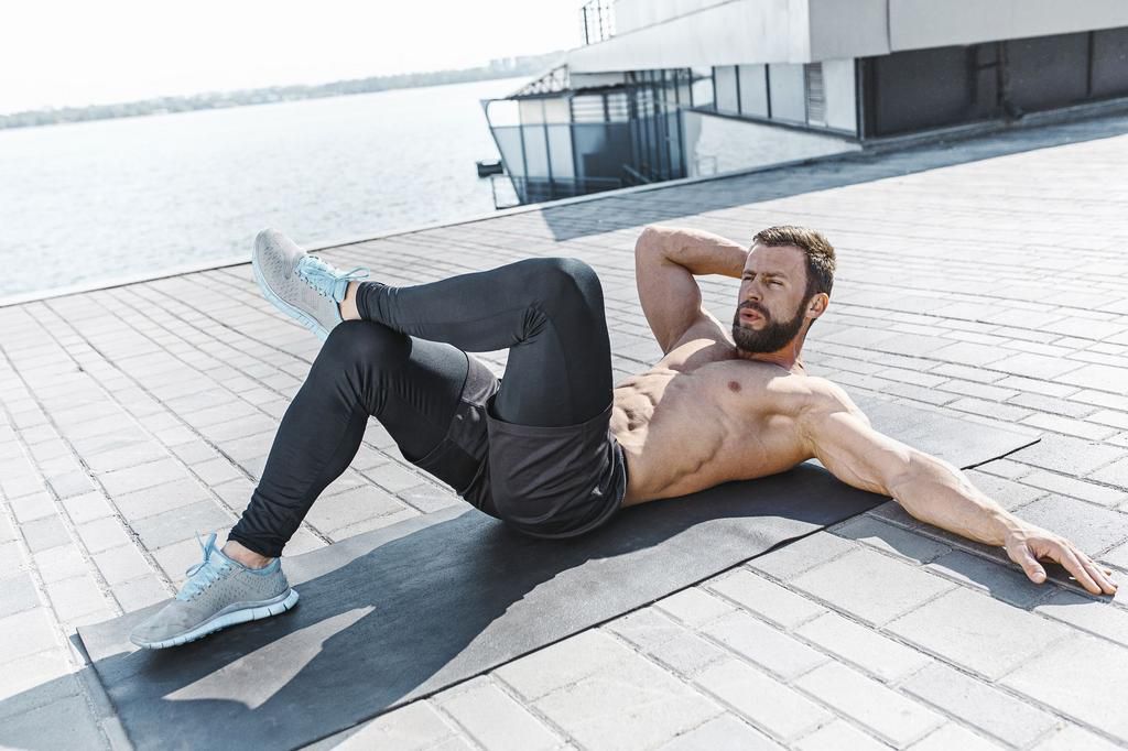 Fit fitness man doing fitness exercises outdoors at city