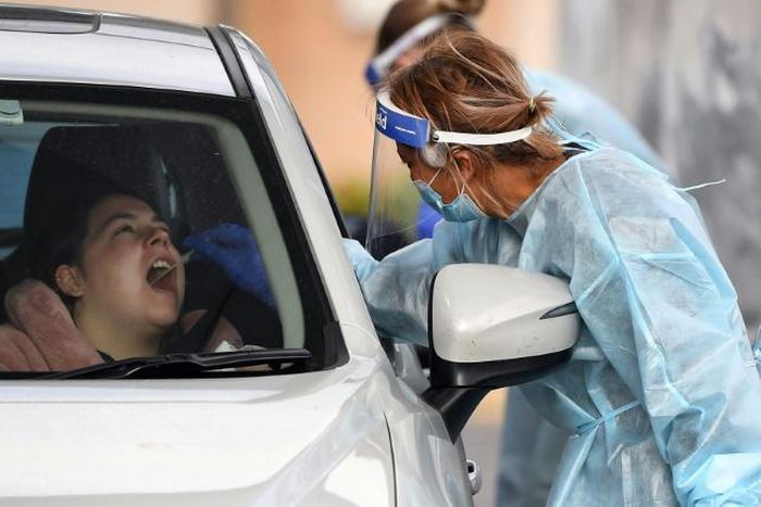 A coronavirus tester takes a swab sample at a drive-through testing station in Melbourne