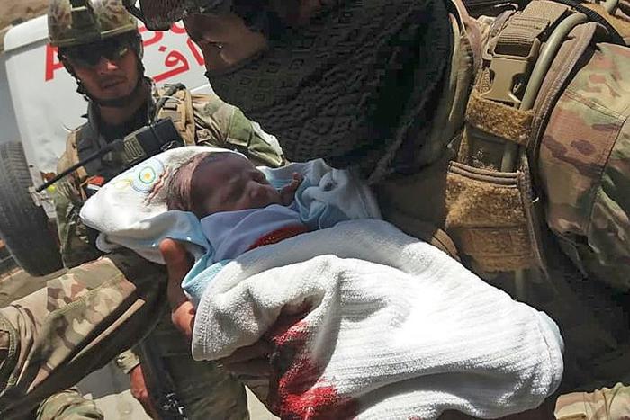 A member of the Afghan security forces carries a baby from a maternity hospital in Kabul that was attacked by gunmen on Tuesday