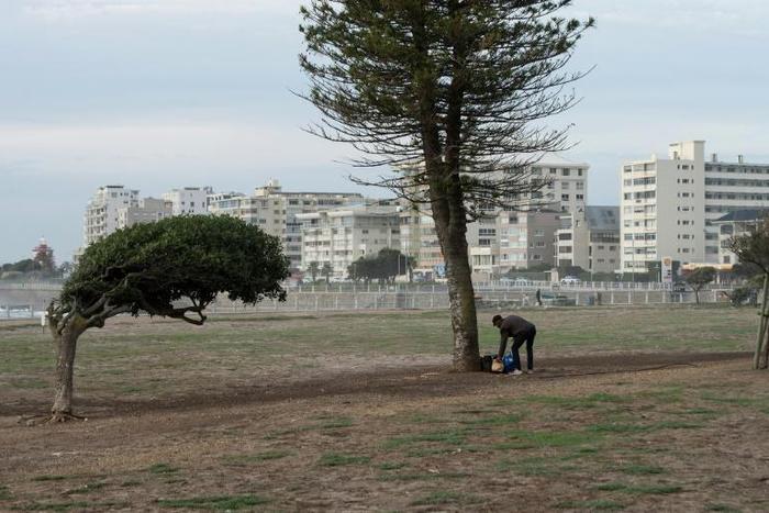 A homeless man stands with some of his belongings at a usually busy promenade in Capetown, now mostly deserted because of the coronavirus lockdown