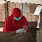 A woman in Djibouti selling khat leaves, a mild stimulant, wears a mask and gloves to ward off the COVID-19 illness