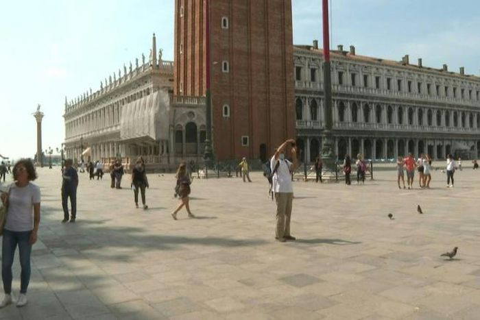 People walk around St Mark's Square in Venice, Italy, with some taking pictures of the famous sites as the country reopens to tourists from Europe after a months-long coronavirus lockdown