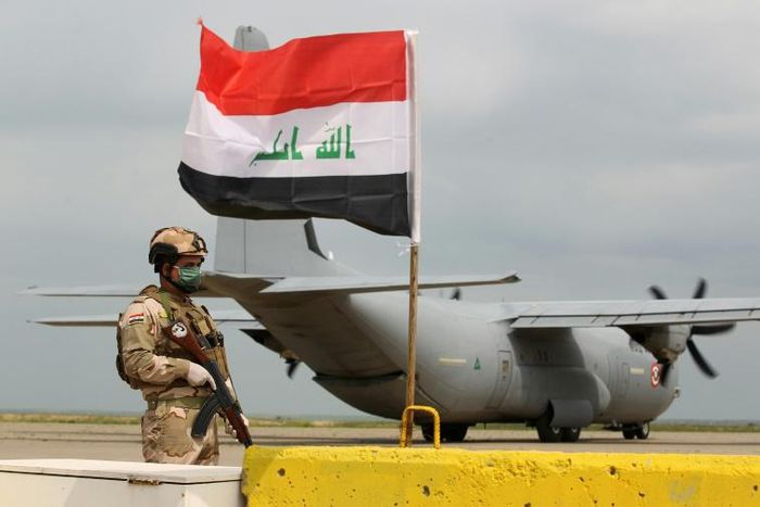 An Iraqi soldier stands guard in front of a US military air carrier at the Qayyarah air base, near Mosul in northern Iraq, on March 26, 2020. The US says it will reduce troops in the country "over coming months"