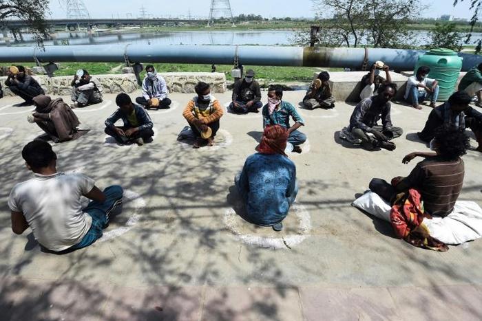 Homeless Indians sit in "isolation circles" outside a shelter while waiting for food in New Delhi