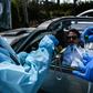 Health workers administer a test for coronavirus at a drive-through facility in West Palm Beach, Florida