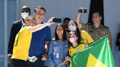 Brazilian President Jair Bolsonaro and his daughter Laura (C) pose for a selfie with supporters outside his residence in Brasilia on Sunday