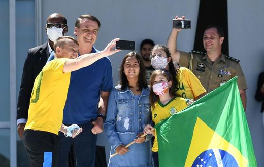 Brazilian President Jair Bolsonaro and his daughter Laura (C) pose for a selfie with supporters outside his residence in Brasilia on Sunday