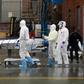Medical personnel move a deceased patient to a refrigerated truck serving as a makeshift morgue in Brooklyn