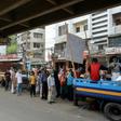 People queue to collect subsidised food in Dhaka