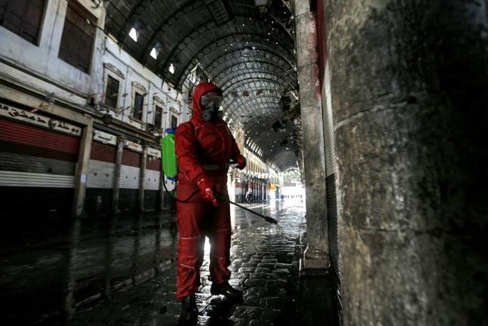 A Red Crescent member sprays disinfectant along an alley of the historic Hamidiya souk (market) in the old city of Syria's capital Damascus as part of efforts against the coronavirus pandemic