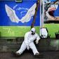 An Indonesian health agency official rests at the entrance to a public toilet as other colleagues conduct COVID-19 testing in Bandung, West Java