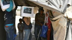 Volunteers deliver aid at a camp for displaced Syrians near the town of Deir al-Ballut in Aleppo province, by the border with Turkey, April 14, 2020 during the coronavirus pandemic