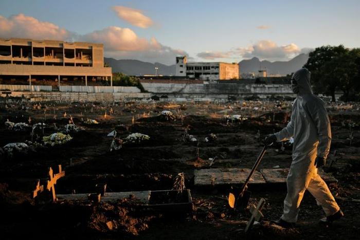 A funeral worker wearing protective clothing as a preventive measure against the coronavirus walks through Caju Cemetary in Rio de Janeiro on May 9