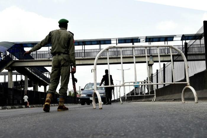 A Nigerian police officer in Lagos flags down an oncoming vehicle at a checkpoint to enforce an extended lockdown as part of measures to prevent the spread of COVID-19