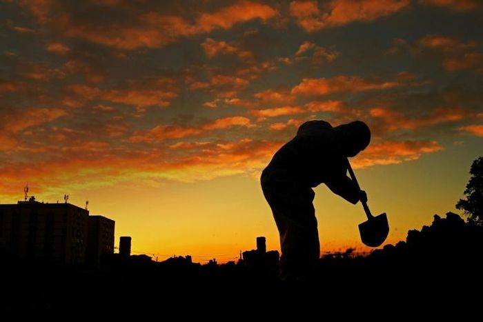 A worker wearing protective clothing digs a grave for a coronavirus victim at the Caju cemetery in Rio de Janeiro, Brazil on May 28, 2020