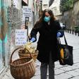 A woman puts food in a solidarity basket displayed with a note reading, "Who can put, who cannot take" in Naples, as Italy sees evidence it may have made it through the worst of the coronavirus pandemic