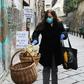 A woman puts food in a solidarity basket displayed with a note reading, "Who can put, who cannot take" in Naples, as Italy sees evidence it may have made it through the worst of the coronavirus pandemic